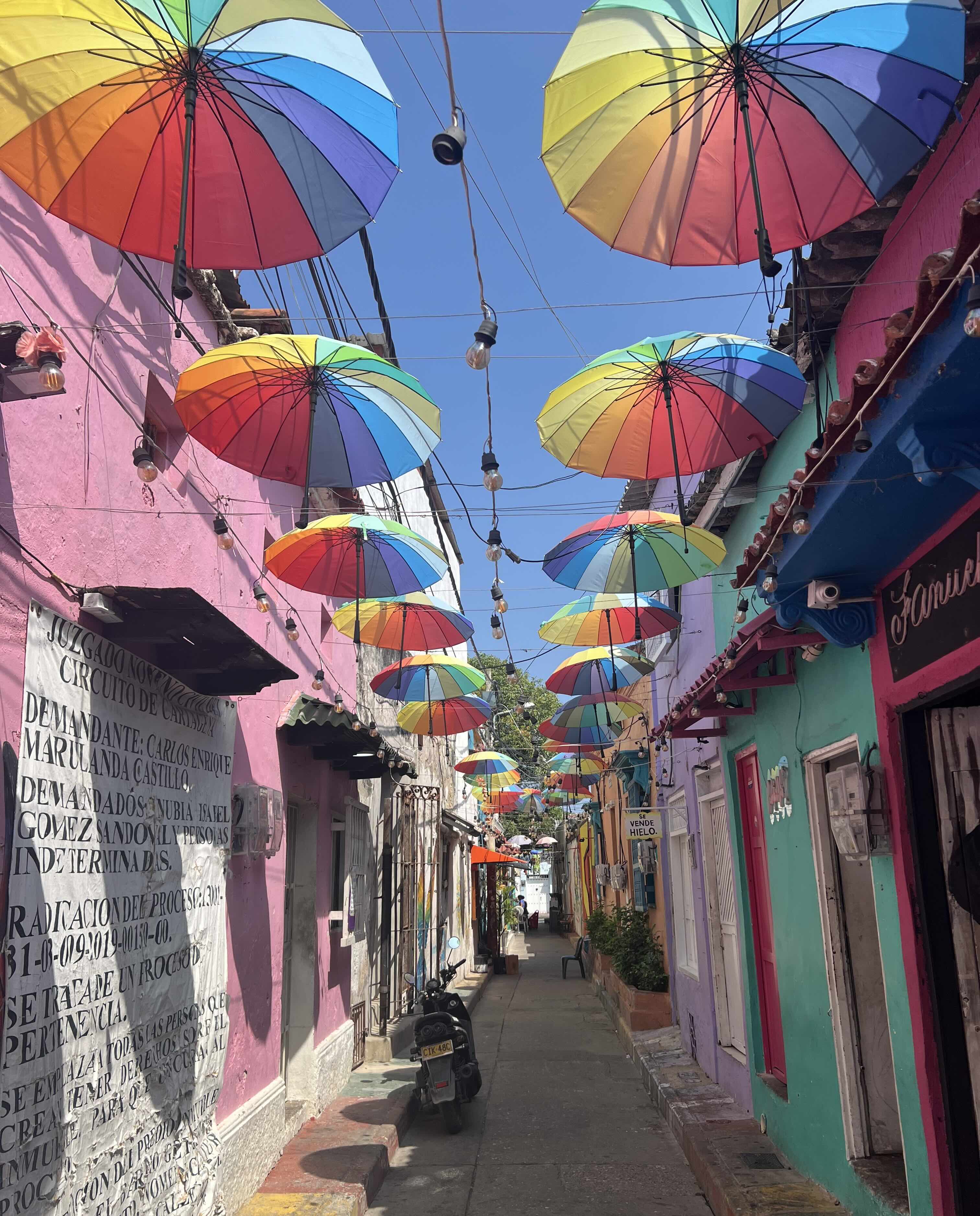 A colorful street in Getsemaní, Colombia, lined with bright umbrellas and colorful buildings.